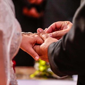 Groom placing ring on brides finger.